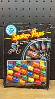 Front of sealed Spokey Pops package showing colorful plastic bike wheel spinners attached to backing card.