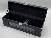 Open view of the rectangular black faux leather bottle storage case showing the interior strap and lined inside.
