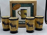 Four Brushwerks moose mugs with packaging box behind them showing product image and branding