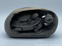 Front view of the carved stone sculpture showing the two turtles inside an oval-shaped stone piece.