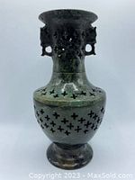 Front view of dark green jade vase showing perforated carved pattern and curved flared rim