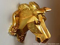 Front angled view of gold geometric horse head wall decor showing embossed swirl patterns and detailed mane and facial features.