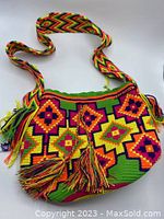 Front view of the brightly colored multicolour bucket bag with visible tassel details, strap stretched out to show pattern and length.