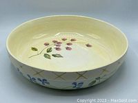 Top and inside view of the bowl showing pale yellow interior with handpainted raspberries and leaves.