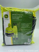 Image showing the packaged John Deere ANSI Class III rain suit with yellow color and product details on the back.