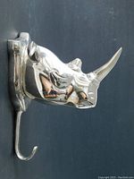 Side angle view of the silver metal rhinoceros head with a single curved hook beneath the head for hanging items.