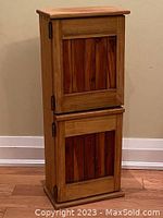 Front view of rustic wood storage cabinet showing two closed doors with rustic wooden panels and metal hinges, standing on the floor.
