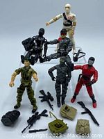 Seven G.I. Joe poseable action figures with assorted weapons and backpacks displayed on white background.