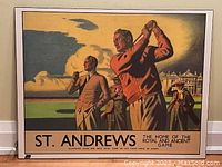 Full view of reproduced British Railways advertising poster for St Andrews golf on fibreboard, showing title, artwork of men around a golfer swinging, and background clubhouse.