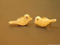 Front view of the pair of bird-shaped stud earrings made of carved mother of pearl from abalone shells showing the detailed carving and lustrous surface.