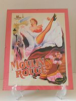 Front view of vintage reproduction Moulin Rouge 1952 movie poster in glass frame on rose/pink mat