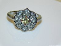 Front view of the vintage art deco style ring showing the round pale yellow citrine central stone surrounded by flower petal shapes with clear stones and silver plating.
