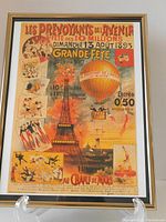 Framed reproduction vintage Art Nouveau French advertising poster featuring the Eiffel Tower, hot air balloon, and performing figures, with clear sharp image and gold-tone frame with black mat.