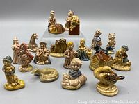 Photo of 20 assorted vintage Wade ceramic miniature figurines including nursery rhyme characters and animals arranged on a gray background.