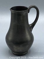 Photo showing front view of vintage pewter jug with handle, dark matte finish, bulbous body shape
