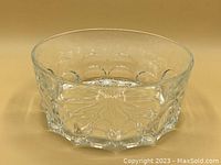 Clear glass bowl showing embossed thumbprint shaped oval designs on outer walls with flower pattern embossed on the interior base.