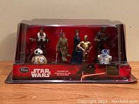 Front view of sealed box with all seven figurines displayed, showing characters and packaging details.