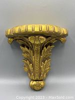 Front view of the gold ornate wall shelf highlighting leaf and floral design with distressed finish.