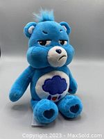 Front view of blue Grumpy Care Bear plush with distinct frowning facial features and cloud-heart belly badge