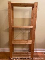 Full view of IKEA wood storage unit showing vertical slats and horizontal shelves with metal cross braces at back.