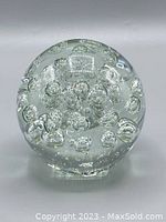 Clear spherical glass paperweight featuring multiple internal bubbles of varying sizes on a flat base.