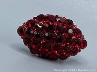 Close-up of the large ruby red rhinestone cluster on the ring, showing the faceted stones and setting.
