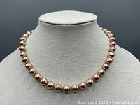 Front view of the necklace displayed on a bust stand showing the entire strand with knotted pink pearls and the length.