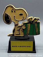 Front view of Snoopy trophy holding gift box with greeting plate on base