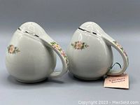 Side view showing the curved shape and rose floral pattern on the shakers with handles