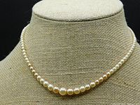 Single-strand cream-coloured pearl necklace on display bust, showing overall design and graduation.