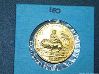 Close up front view of Leo zodiac coin in plastic sheath within blue card labeled LEO.