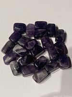 Overview of 18 natural amethyst gemstone beads in various purple shades showing drilled holes