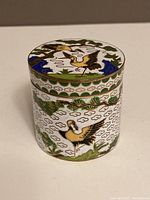 Front and side view of small cylindrical cloisonné box with crane and cloud designs, showing intact enamel and colors.