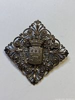 Front view of the antique French silver brooch showing ornate filigree and Chatillon crest on face