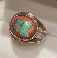 Top-down close-up of boulder opal sterling silver ring showing two opal stones on reddish matrix with fire colors and silver band.