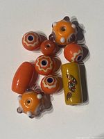 Top view of assorted bright orange Murano style glass beads showing various bead shapes and details including nodules and painted motifs.