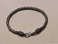 Top down view of closed sterling silver Byzantine chain bracelet showing chain links and clasp