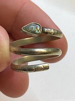 Close-up of the silver-toned snake ring showing the teardrop-shaped iridescent shell in the head and hammered texture on the body.