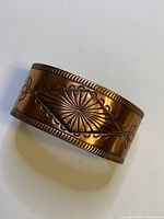 Copper southwestern style bangle showing central diamond embossed design and textured edges