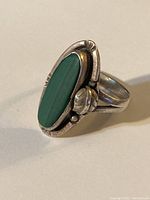 Close-up front view of the sterling silver ring showing the elongated oval green malachite stone set in decorative bezel with floral and bead details.