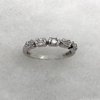 Front view showing five alternating baguette and round diamond clusters on band