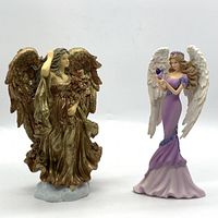 Photo showing two angel figurines side by side on a flat surface with a white background.