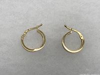 Pair of gold hoop earrings laid flat on white background
