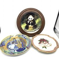 Photo showing three decorative plates including the panda framed plate, Christmas Bells plate, and Julpoesi 1979 nativity plate