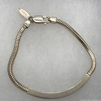 Full bracelet with snake chain and curved rectangular bar lying flat on a white surface showing the entire design.