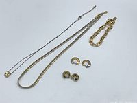 Full lot of jewelry including necklaces, bracelet, and earrings displayed on white background, showing overall condition and variety.