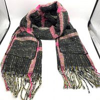 Full view of black-yellow-fuchsia fringe blanket scarf with pockets, folded and laid flat showing fringe ends and striped pattern.