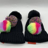 Two black BP brand beanies with large black pom and interchangeable colorful poms laid side by side.