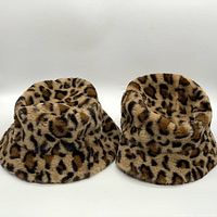 Two leopard print faux fur bucket hats displayed side by side 