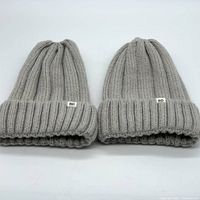 Two grey wide rib knit beanies placed side by side showing the folded cuffs and BP tags